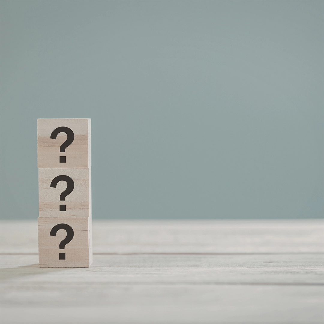 Drei aufeinander gestapelte Holzblöcke mit Fragezeichen symbolisieren Unsicherheit, offene Fragen und den Wunsch nach Orientierung bei der Auswahl passender Inhaltsstoffe.