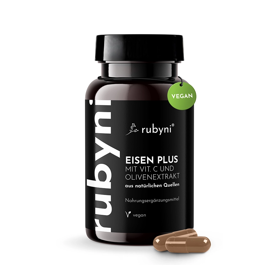 PET-Dose des rubyni Nahrungsergänzungsmittels „Eisen Plus“ mit Vitamin C und Olivenextrakt sowie zwei braunen Kapseln davor auf neutralem Hintergrund.