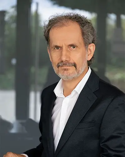 Porträt von Dr. Martin Müller im dunklen Sakko und weißen Hemd vor weißem Hintergrund.