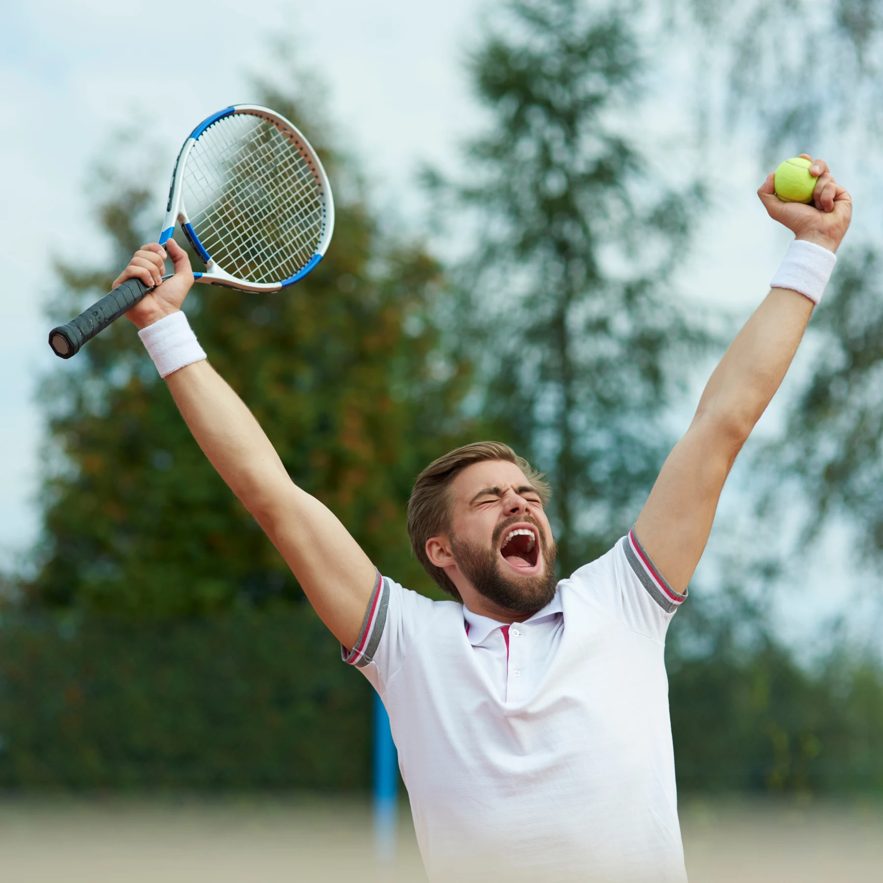 Tennisspieler jubelt mit erhobenem Tennisschläger und Tennisball auf dem Platz.