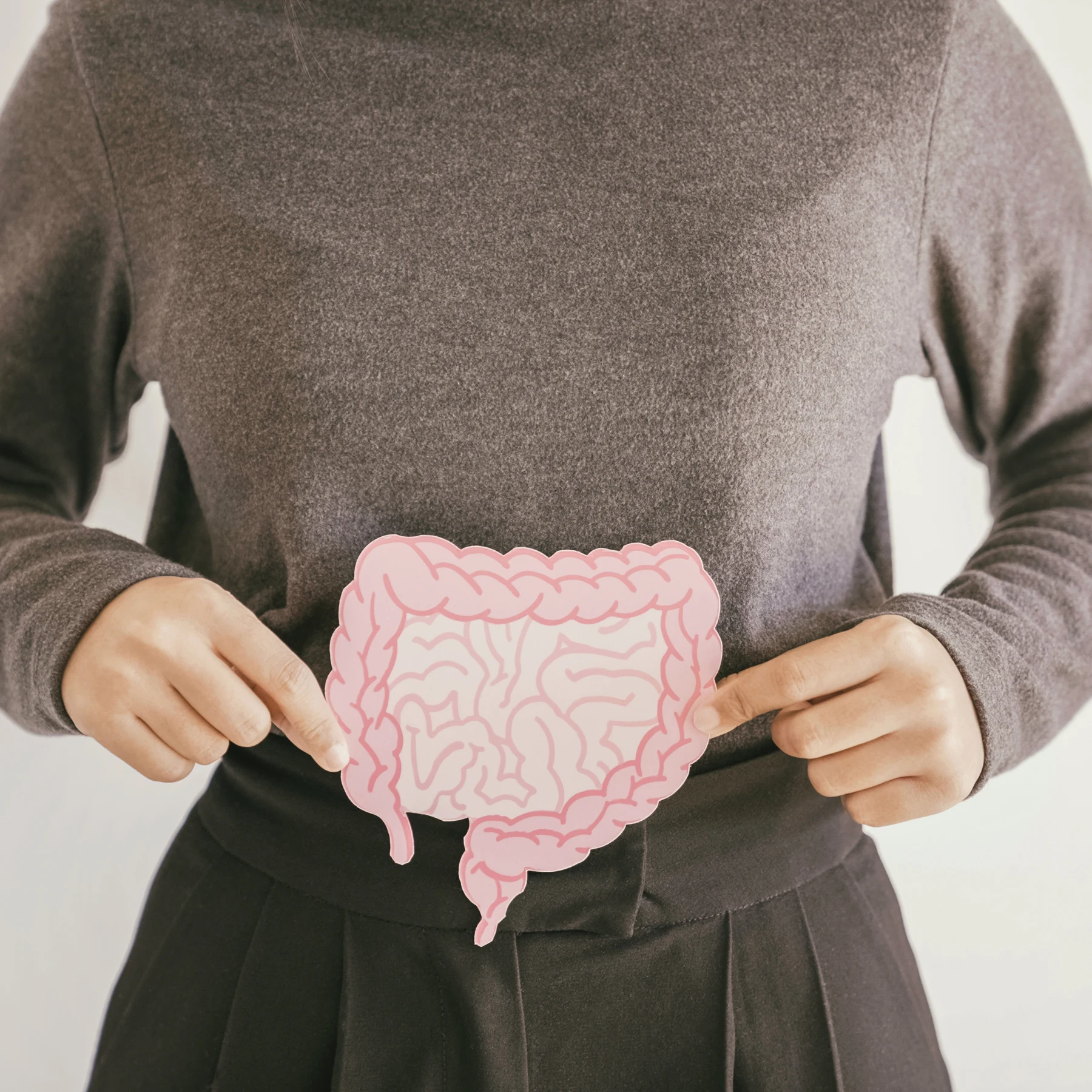 Person hält eine Illustration des menschlichen Darms vor den Bauch.