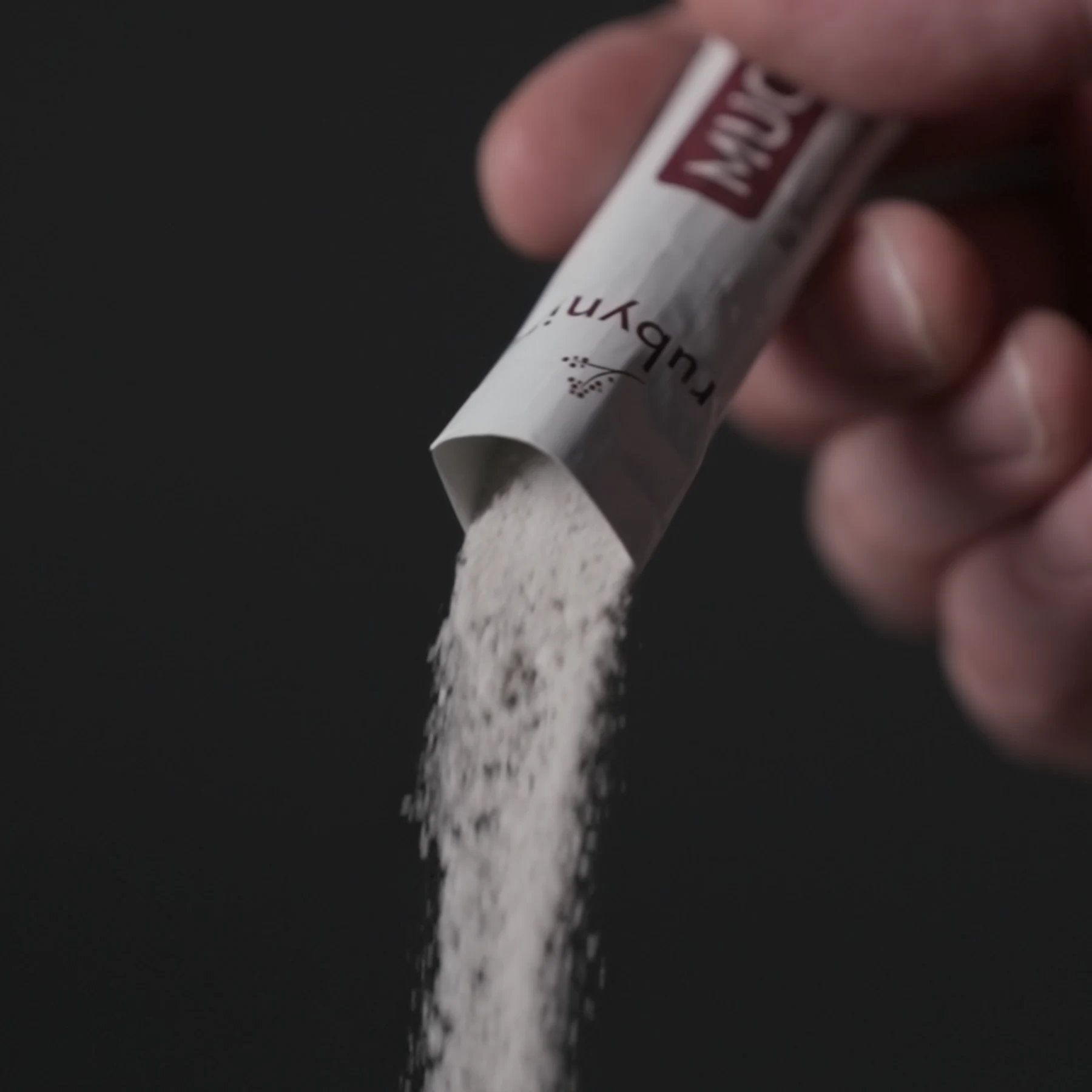 Ballaststoffpulver wird aus einem Portionsstick von rubyni® Mucosa ausgeschüttet.